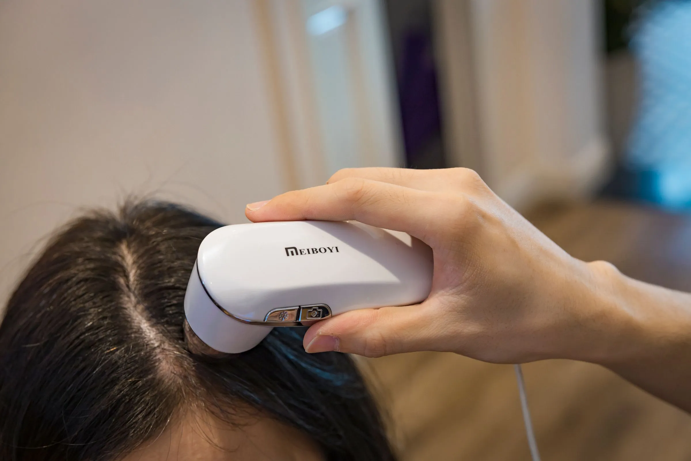 A handheld scalp camera being moved through a patient's hair