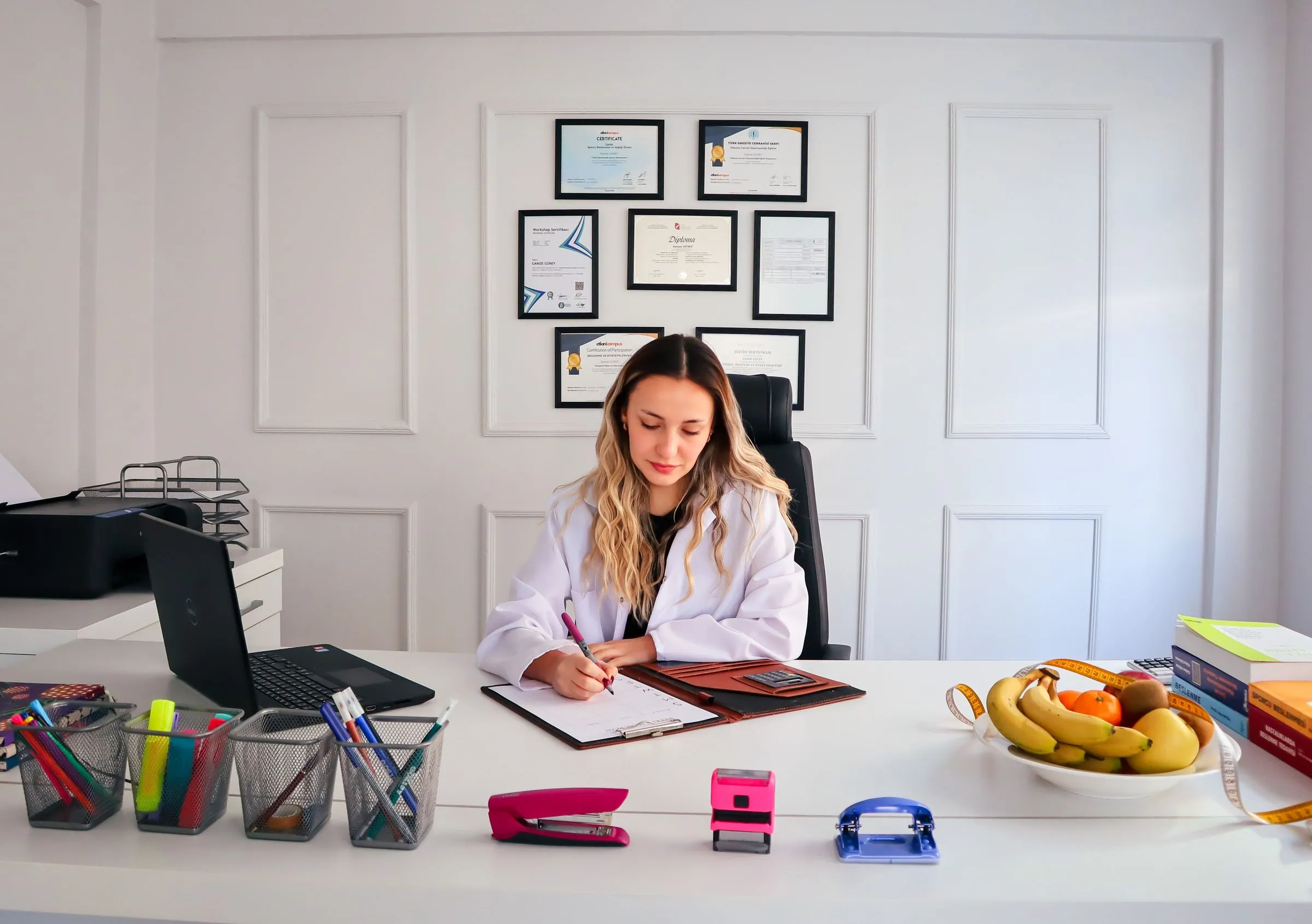 A dietitian writing at a desk with fresh fruit beside her