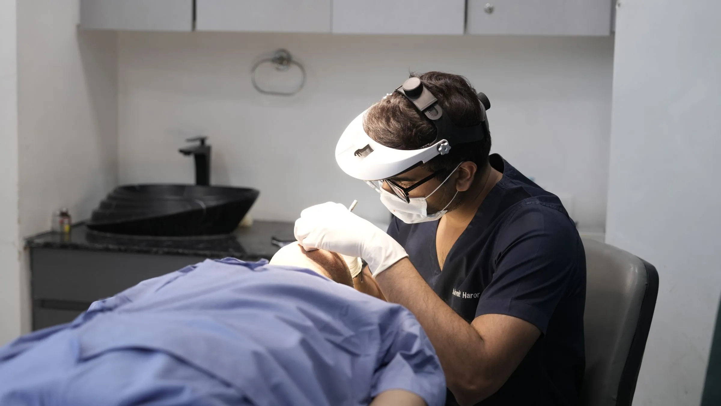 A dermatologist wearing a headlamp performing a minor skin procedure