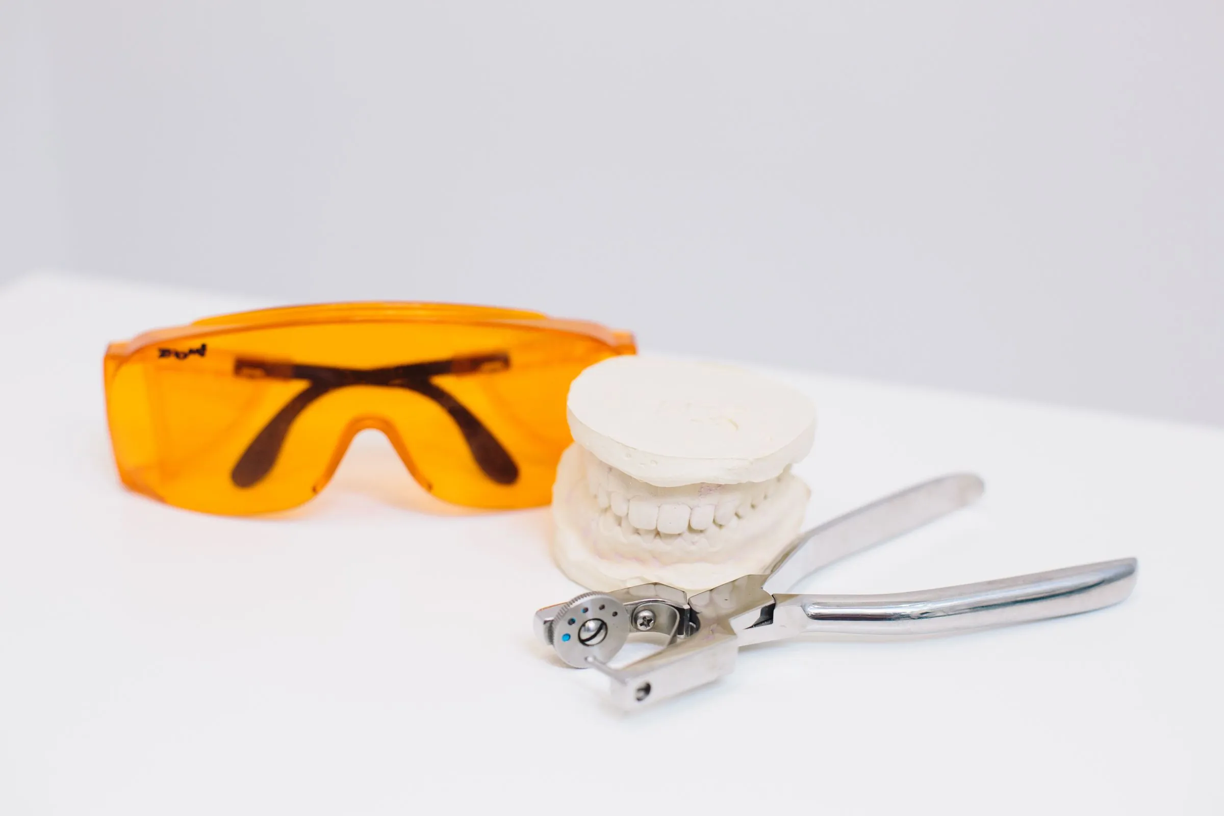 Protective eyewear, a dental cast and extraction forceps on a clean surface