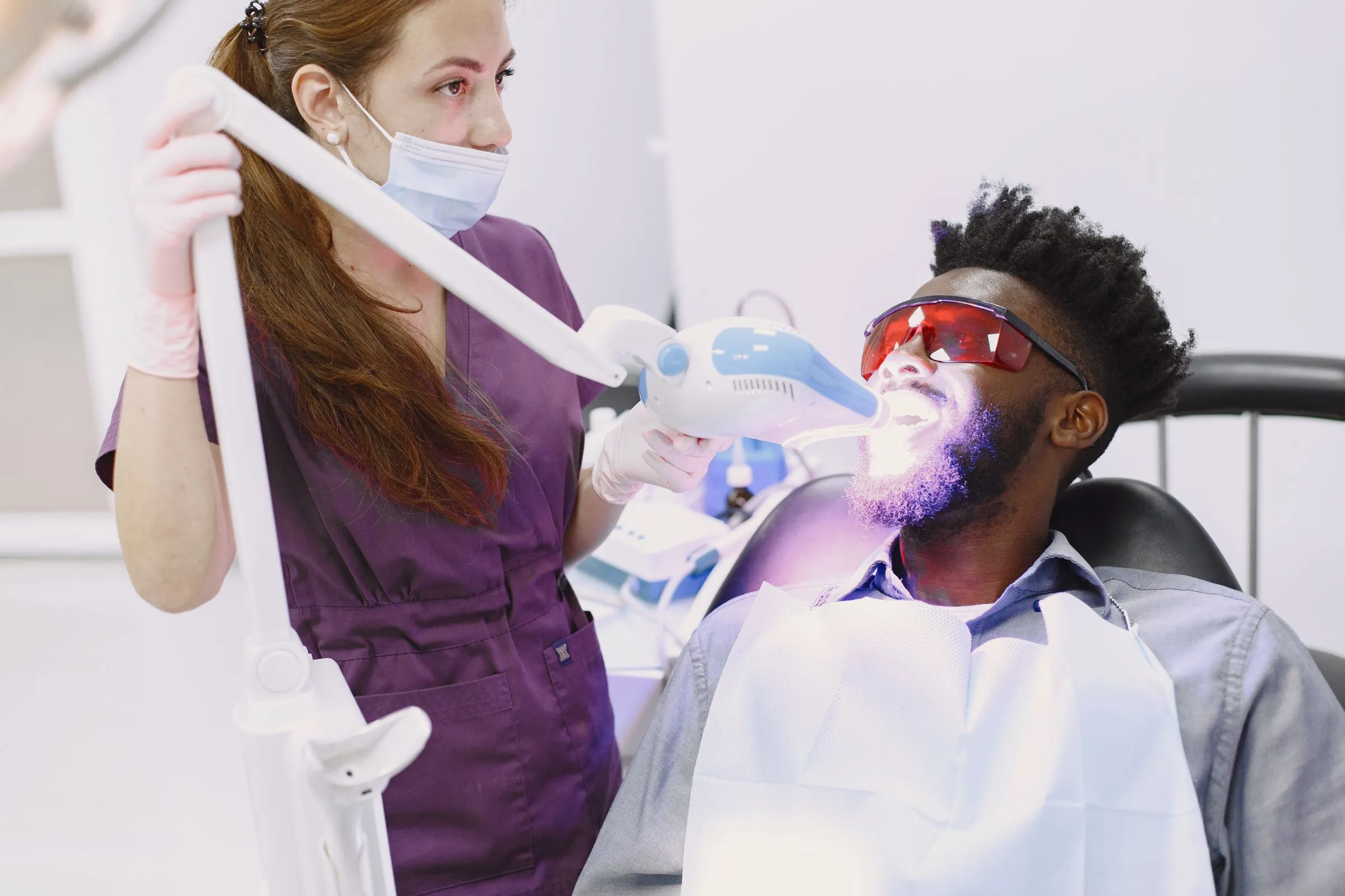 A patient in protective goggles during an in-chair whitening procedure