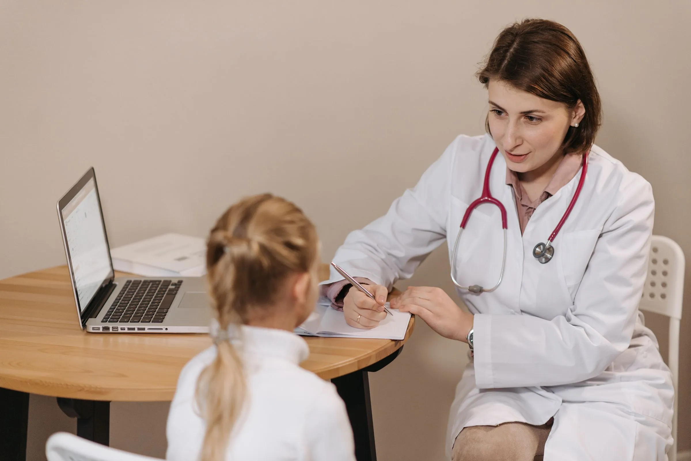 A doctor talking with a young child at a consulting room desk