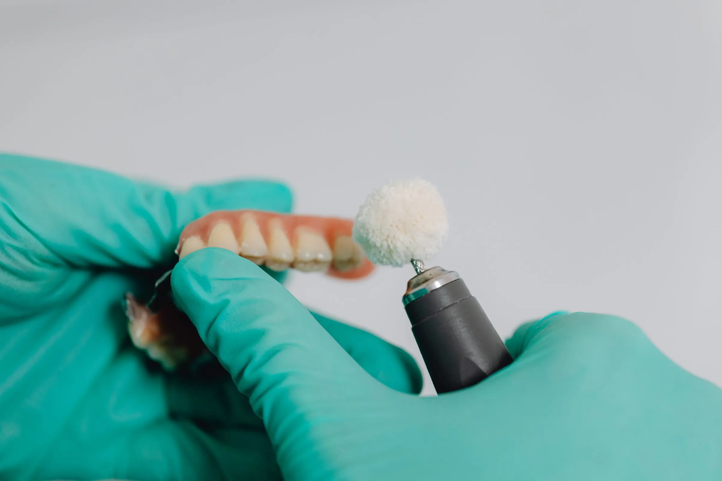A dentist polishing a dental prosthesis with a rotary tool
