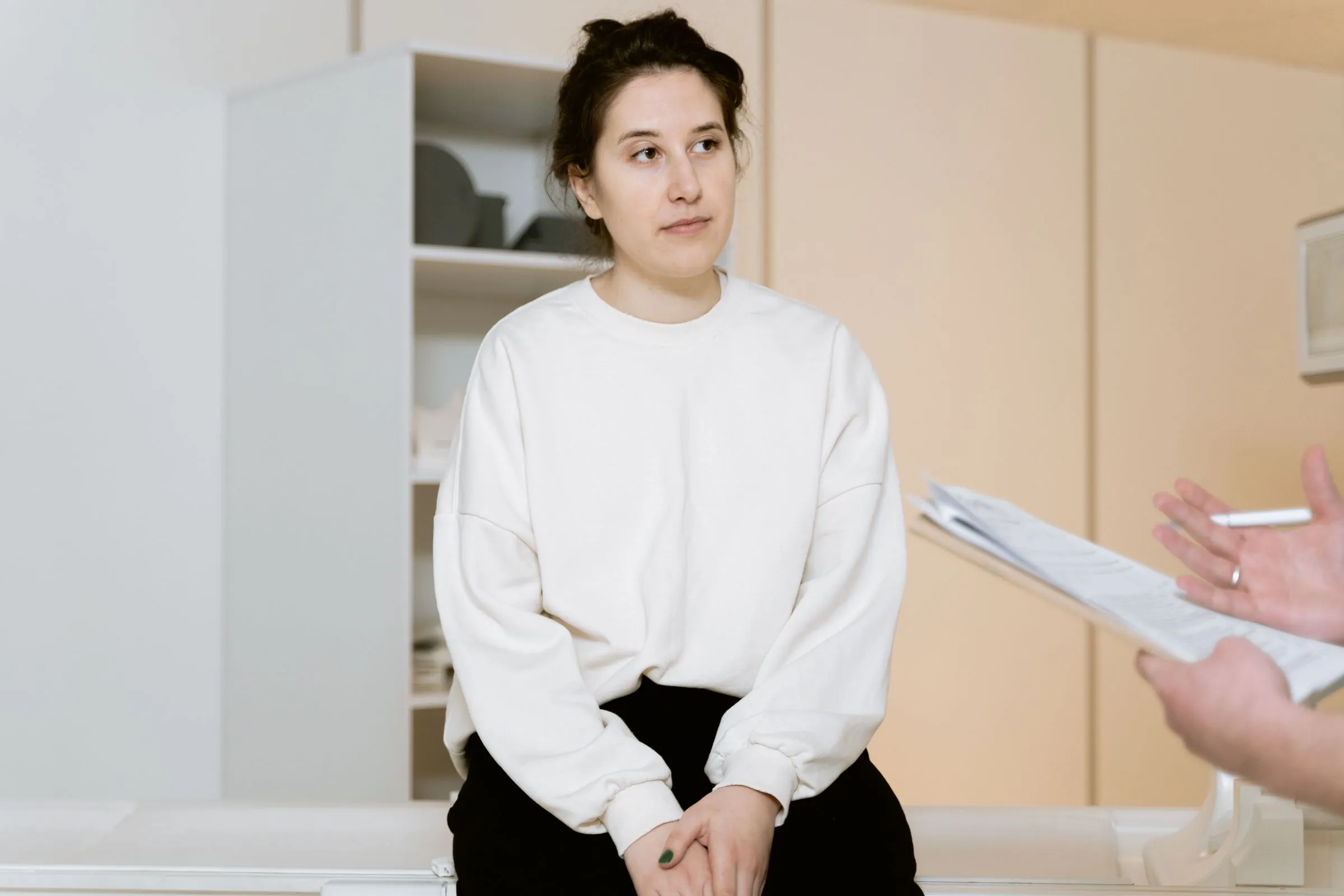 A patient seated in a consulting room while a clinician takes notes