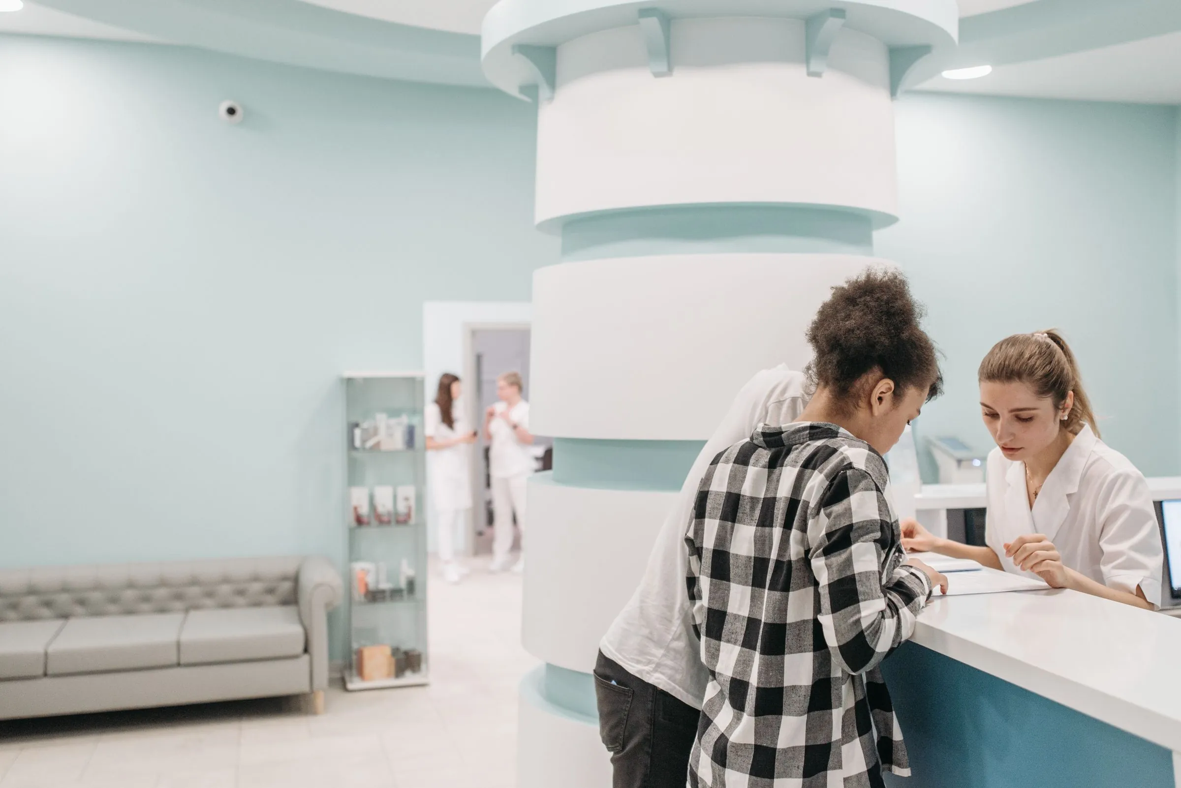Staff assisting a patient at a modern clinic reception desk