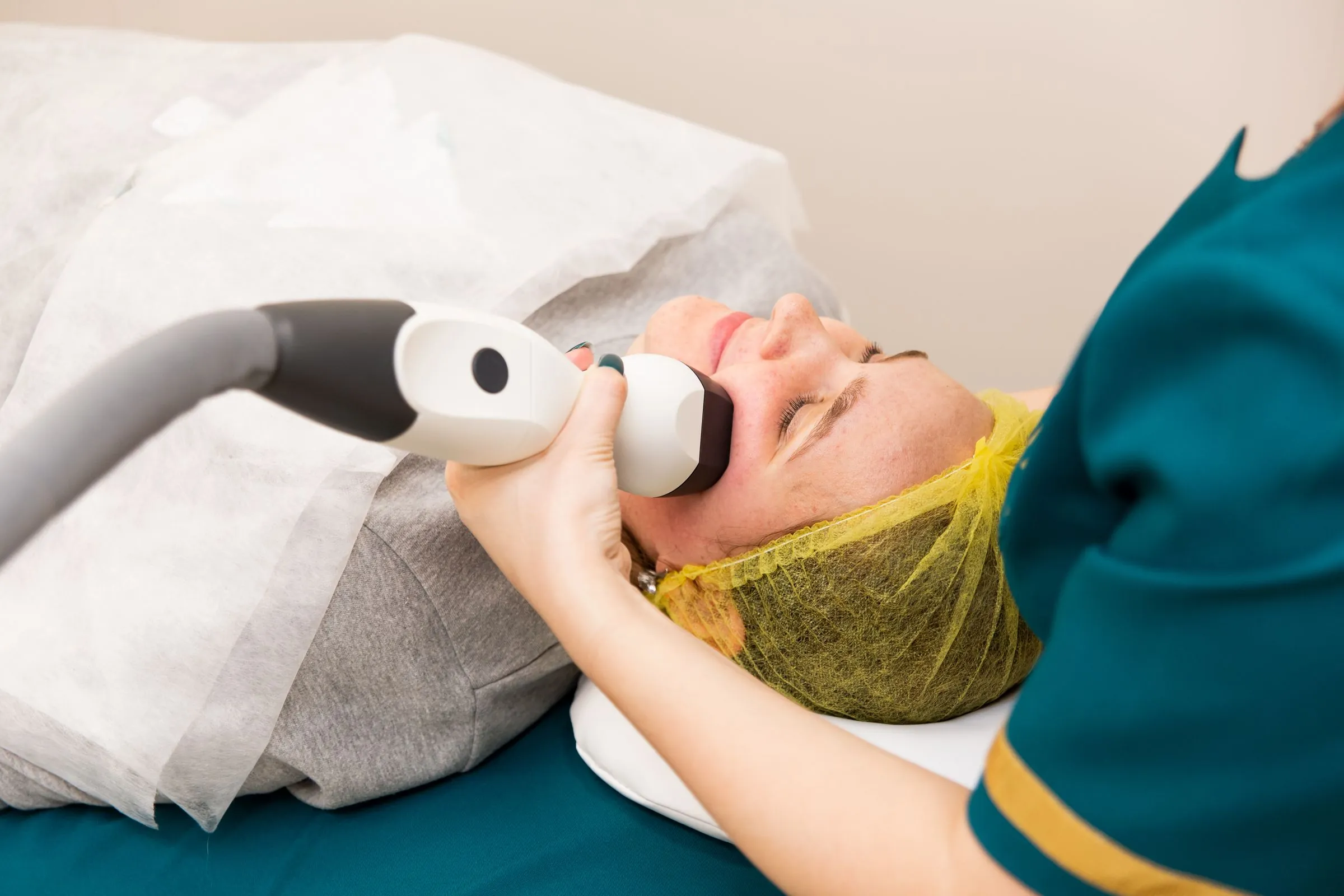 A clinician using a handheld device during a facial treatment