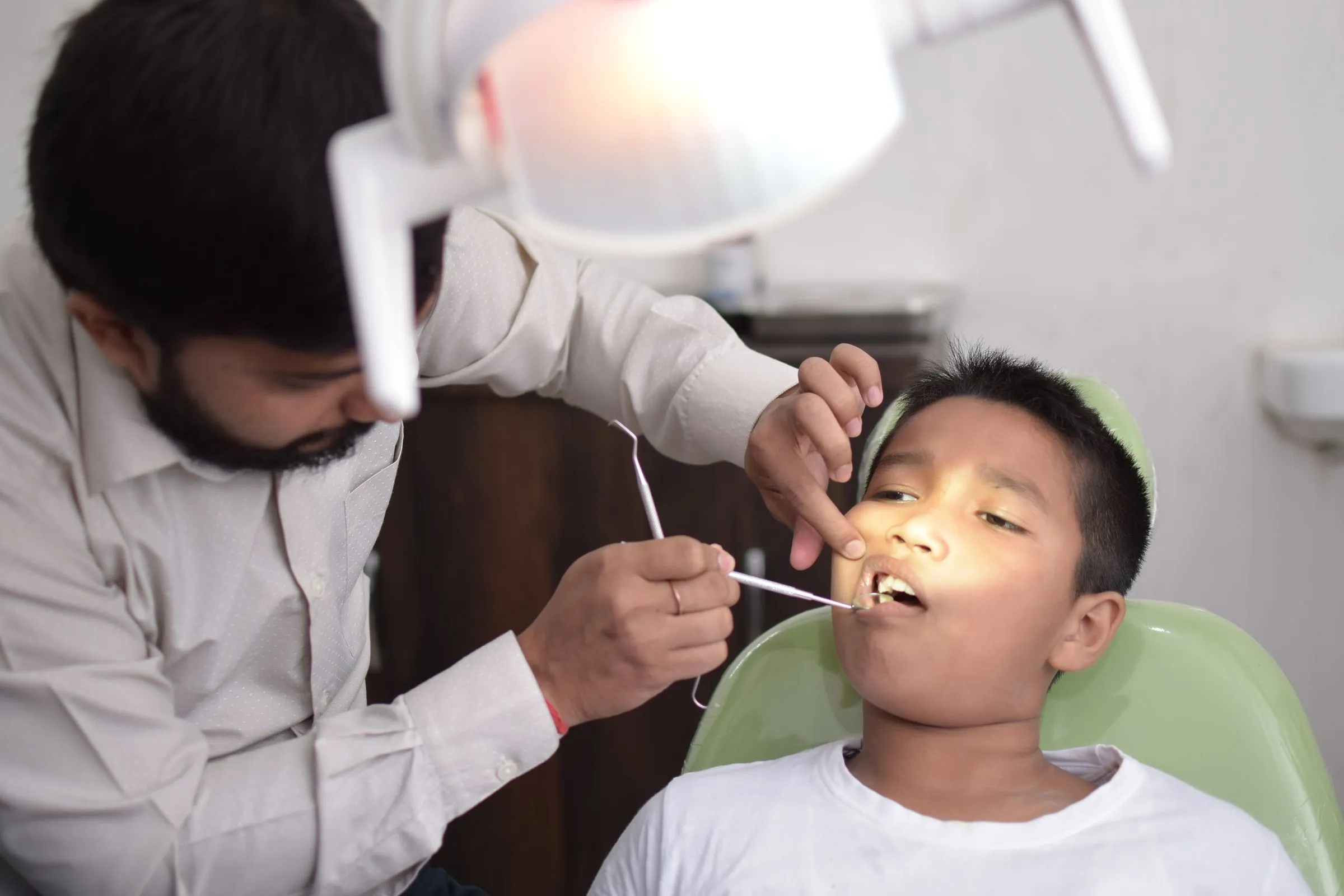 A dentist examining a child's teeth in a bright surgery