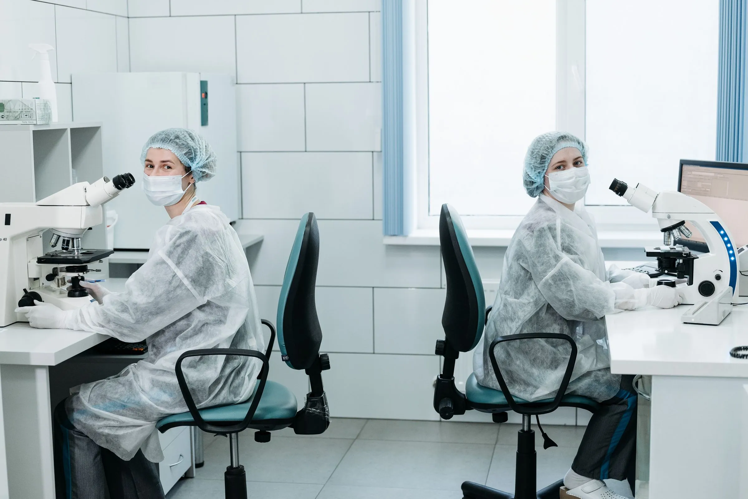 Two laboratory scientists working at microscopes