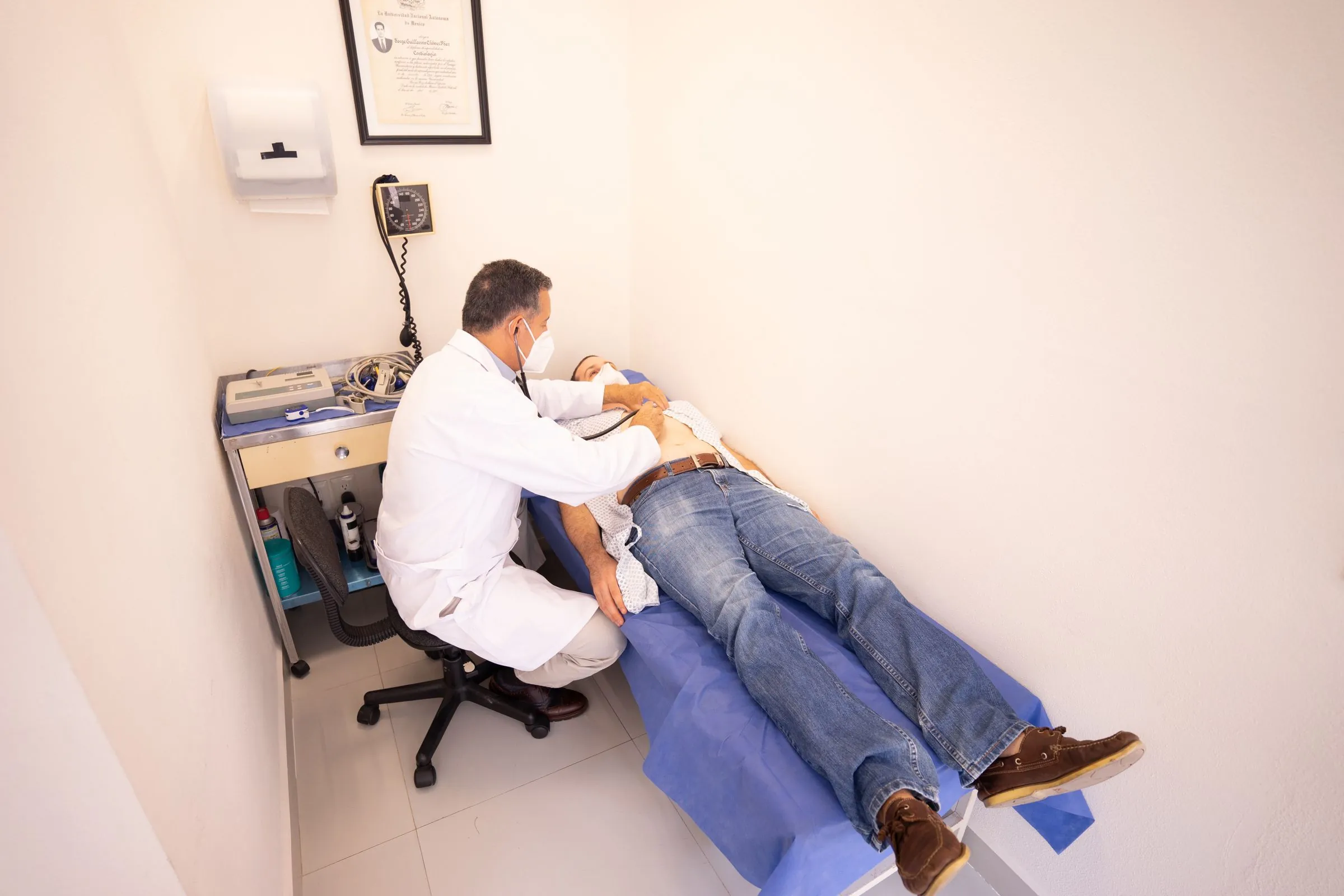 A doctor examining a patient on a couch in a consulting room