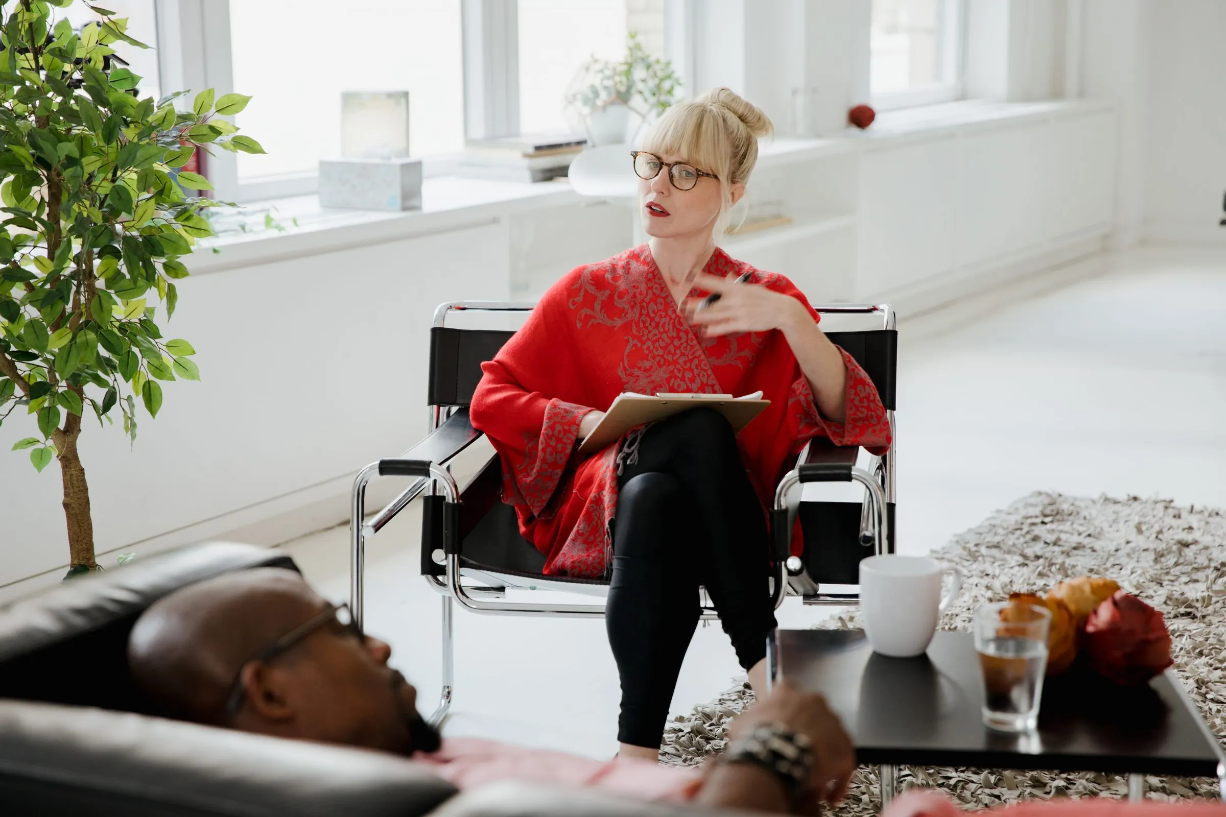 A clinician taking notes in a bright, plant-filled consulting room